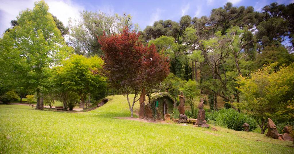 Gramado baixo, com uma porta redonda e diversas arvores nas proximidades