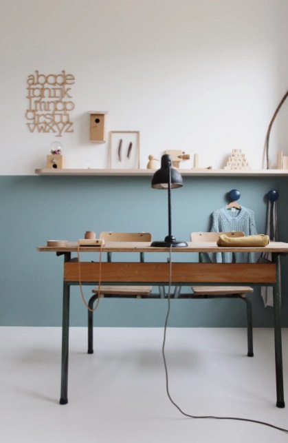 como-a-gente-mora-home-office-03 Home office com parede meia colorida em azul. Quadros na prateleira de madeira que marca a divisão entre a parte azul e a parte branca da parede. Mesa em madeira.