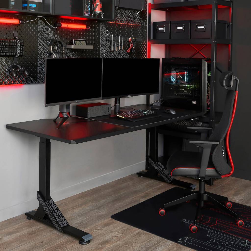 ikea-lanca-colecao-de-moveis-para-e-sports-casa.com-2 Mesa preta com dois monitores de computadors. Na parede, um mural com acessórios, como fone, teclado e ferramenta. Na lateral, uma estante com a CPU. E uma cadeira gamer com detalhes vermelho.