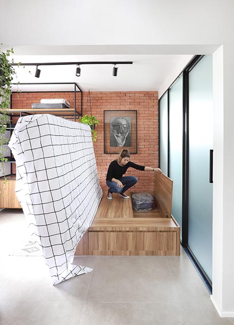 apartamento-de-30-m²-transformado-em-loft-casa.com 29 Quarto Pandora Studio 92 Arq – Fotos Mariana Orsi Colchão sendo levantado mostrando armário para armazenamento abaixo dele