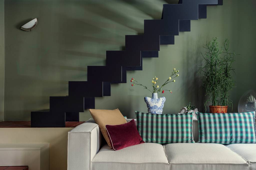 10-interiores-com-decoracao-calma-para-aliviar-o-estresse-casa.com-2 Sala de estar com parede cor verde-musgo Uma escada próxima foi pintada de preto como contraste, criando uma atmosfera temperamental contrastada com as almofadas coloridas do grande sofá