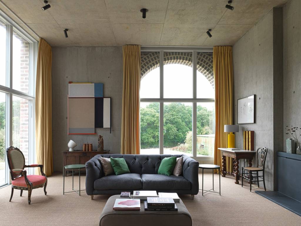 10-interiores-com-decoracao-calma-para-aliviar-o-estresse-casa.com-5 Sala de estar com tetos altos de concreto como um fundo calmo. Uma cadeira de estilo barroco e um banquinho revestido de tecido ajudam a suavizar o espaço.