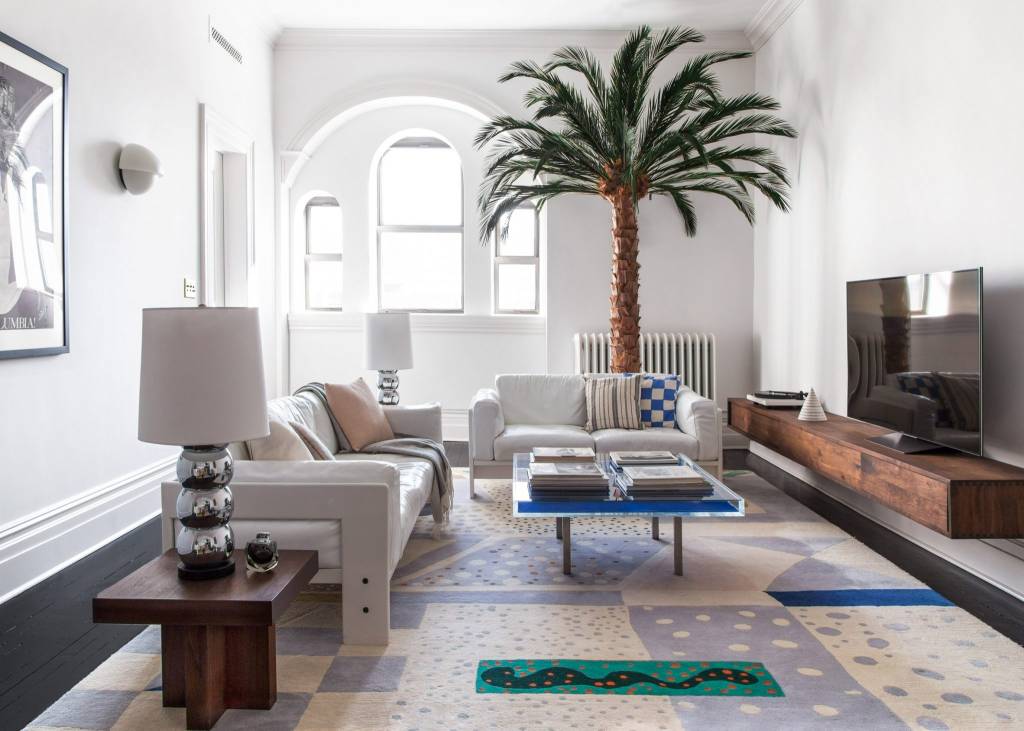 10-interiores-com-decoracao-calma-para-aliviar-o-estresse-casa.com-6 sala de estar com muitos tecidos estampados. Uma grande palmeira é um detalhe divertido e pega a madeira escura de um pequeno aparador e de uma bancada de TV flutuante.
