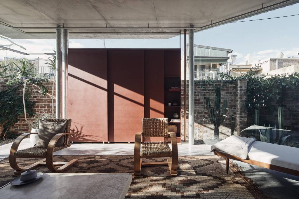 10-interiores-com-decoracao-calma-para-aliviar-o-estresse-casa.com-7 Sala com paredes de vidro, com colunas de metal. A mobília tem o mesmo estilo descontraído, com cadeiras de madeira e um sofá-cama, criando locais de descanso confortáveis.