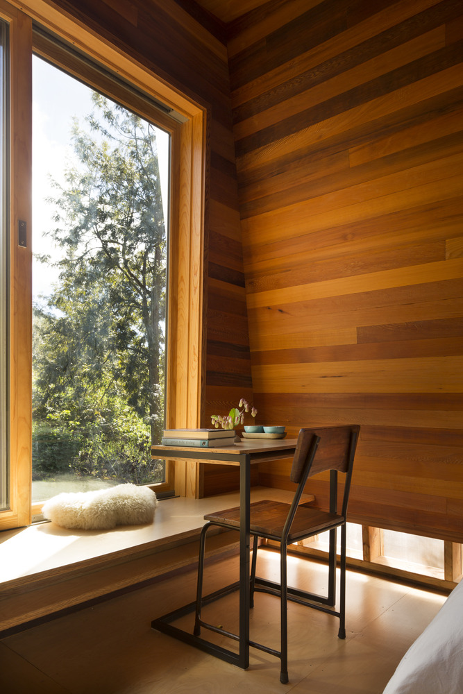 4-casa-de-22-m-2-recebe-projeto-de-visao-ecocentrica-e-de-amor-pela-terra Quarto e home office do pavilhão com vista para a natureza circudante e cadeira, tudo revestido por madeira