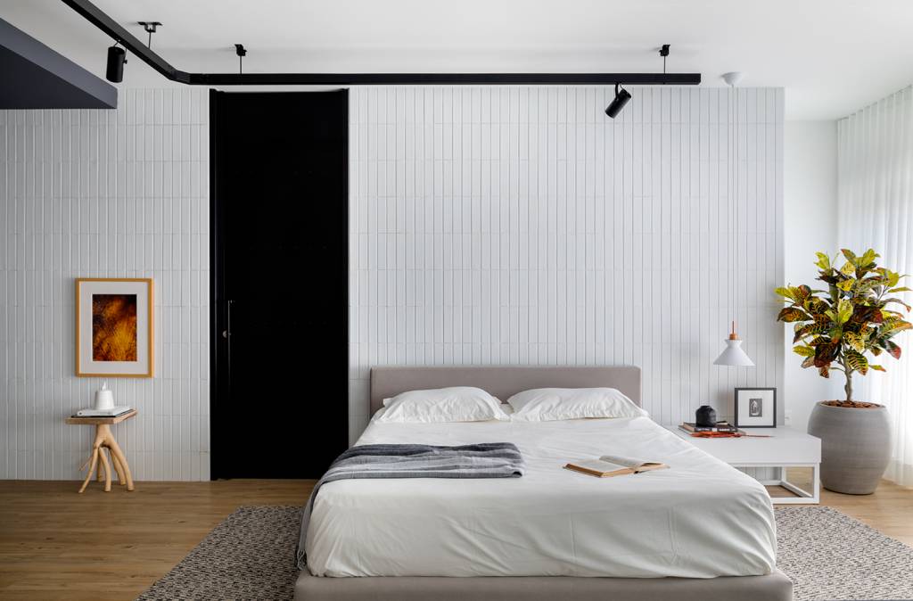 estudio-de-73-m²-com-planta-integrada-e-design-moderno-casa.com-archdaily-studio-gabirel-bordin-fabio-junior-severo-11 Quarto de casal, com cama baixa, em piso de madeira com tapete. Paredes brancas, com uma porta na cor preta