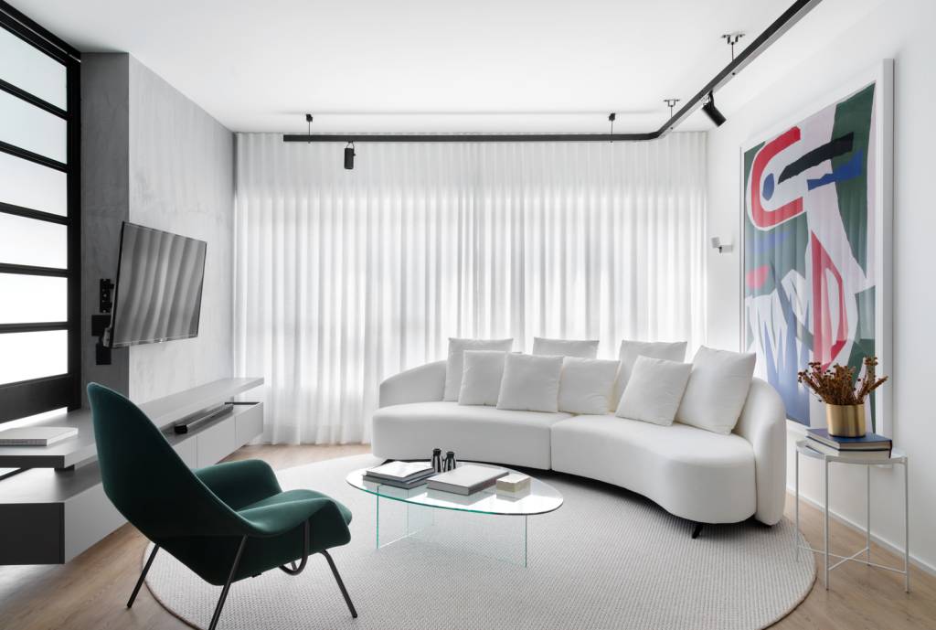 estudio-de-73-m²-com-planta-integrada-e-design-moderno-casa.com-archdaily-studio-gabirel-bordin-fabio-junior-severo-3 Sala de estar com piso de madeira e tapete redondo branco. O sofá, na mesma cor, é curvo e acompanha o movimento do tapete