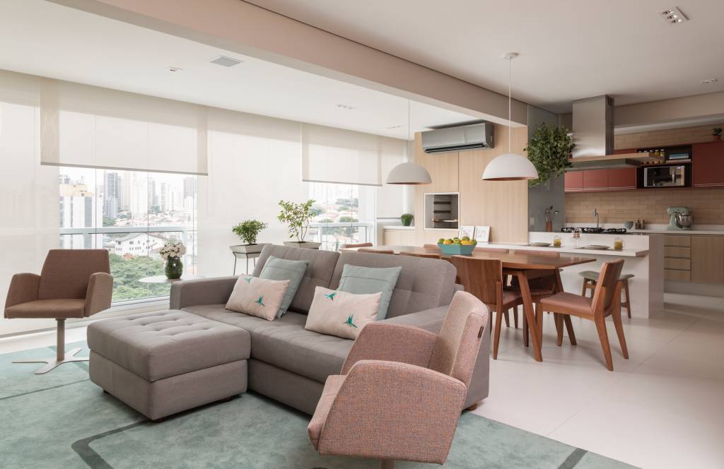 modernidade-e-leveza-no-decor-casa.com _MG_2197 O sofá cinza é adornado com duas almofadas verde claro e duas brancas. No chão, um tapete verde. Uma poltrona em tom rosa claro completa o ambiente. Ao fundo, a mesa de jantar de madeira com cadeira no mesmo material