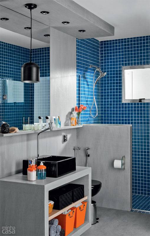 Al&eacute;m de servir de suporte para a ducha higi&ecirc;nica e a papeleira, a meia-parede junto ao boxe propicia privacidade. O rebaixamento de gesso embute tr&ecirc;s spots direcion&aacute;veis e ainda cont&eacute;m uma lumin&aacute;ria pendente, escolha nada convencional para esse tipo de ambiente. &ldquo;Um mero detalhe pode deixar tudo mais charmoso&rdquo;, analisa o arquiteto Rodrigo Costa. A maquiagem e o barbear s&atilde;o beneficiados por l&acirc;mpadas que tenham um bom &iacute;ndice de reprodu&ccedil;&atilde;o de cores (IRC), como a hal&oacute;gena PAR 20 &ndash; ela, por sinal, &eacute; especialmente recomendada para banheiros, pois possui uma blindagem que a preserva da umidade.