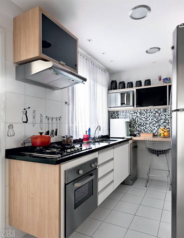 A cozinha com cerca de 10 m&sup2; funciona bem sem mesa, a qual exigiria boa parte da metragem destinada &agrave; circula&ccedil;&atilde;o. Bastou uma bancada no canto para fazer a fam&iacute;lia feliz. Pastilhas de vidro revestem a parede. Projeto de Ana Maria Mouawad Queiroga.