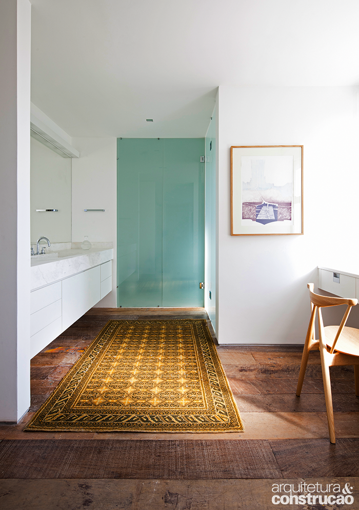 O piso de madeira de demoli&ccedil;&atilde;o e as paredes claras, pintadas de branco, conferem suavidade ao apartamento assinado pelo escrit&oacute;rio AMZ Arquitetos. Abaixo da bancada de m&aacute;rmore pigu&ecirc;s levigado, a marcenaria suspensa de laminado d&aacute; leveza e facilita a manuten&ccedil;&atilde;o do ambiente, que conta ainda com uma penteadeira (&agrave; dir., na foto). J&aacute; o espa&ccedil;o do sanit&aacute;rio (ao fundo) fica preservado por uma discreta porta de vidro jateado, fechamento que se repete no boxe (ao fundo, &agrave; dir.).