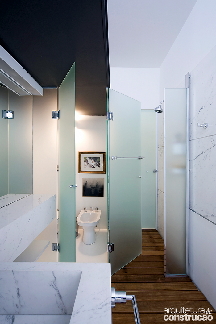 No apartamento de autoria do escrit&oacute;rio Piratininga Arquitetos Associados, a &aacute;rea do lavat&oacute;rio &eacute; uma extens&atilde;o da casa &ndash; e mais de uma pessoa pode usar o espa&ccedil;o ao mesmo tempo. Aqui tamb&eacute;m o m&aacute;rmore pigu&ecirc;s aparece na parede e na bancada. A privacidade no sanit&aacute;rio e no boxe &eacute; garantida por portas de vidro fosco.
