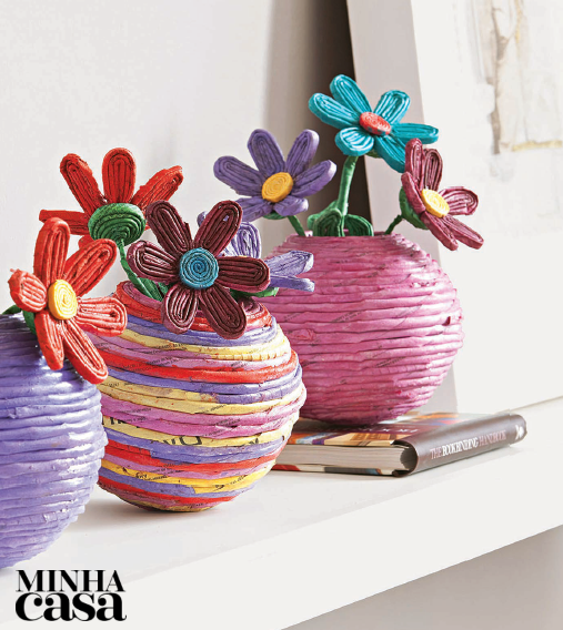 Acrescente um toque de charme à sala com estes vasinhos de flor. Cole os canudinhos de jornal já pintados com guache ao redor de uma bola oca de isopor de 15 cm de diâmetro. Corte o topo da bola para deixar livre a boca do vaso. As flores você faz com tiras mais fininhas e cola branca.