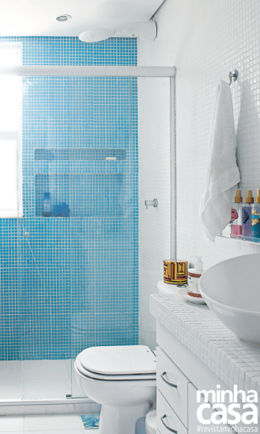 De formatos bastante diferentes, os dois nichos escavados no banheiro deste apartamento de 45 m², em Salvador, resultaram em uma composição muito charmosa! A abertura fininha (60 x 10 x 10 cm*) funciona visualmente como um chapéu para o vão maior abaixo (60 x 10 x 30 cm). Mas não é apenas esse detalhe que encanta no projeto dos arquitetos Gabriel Magalhães e Luiz Cláudio Souza: a pastilha de vidro azul (2 x 2 cm) foi escolhida a dedo para brilhar como água fresca ao receber a luz natural que vem da janela. Pelo formato simples e tamanho diminuto, esse revestimento é sempre uma boa pedida para cobrir superfícies estreitas, por isso é tão usado em projetos desse tipo.