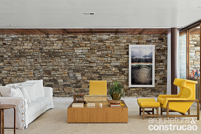 &Eacute; tanta madeira e pedra que a estrutura de a&ccedil;o galvanizado passa despercebida. Nesta imagem da sala, ela evidencia-se no pilar redondo que, sendo marrom, camufla-se no conjunto.