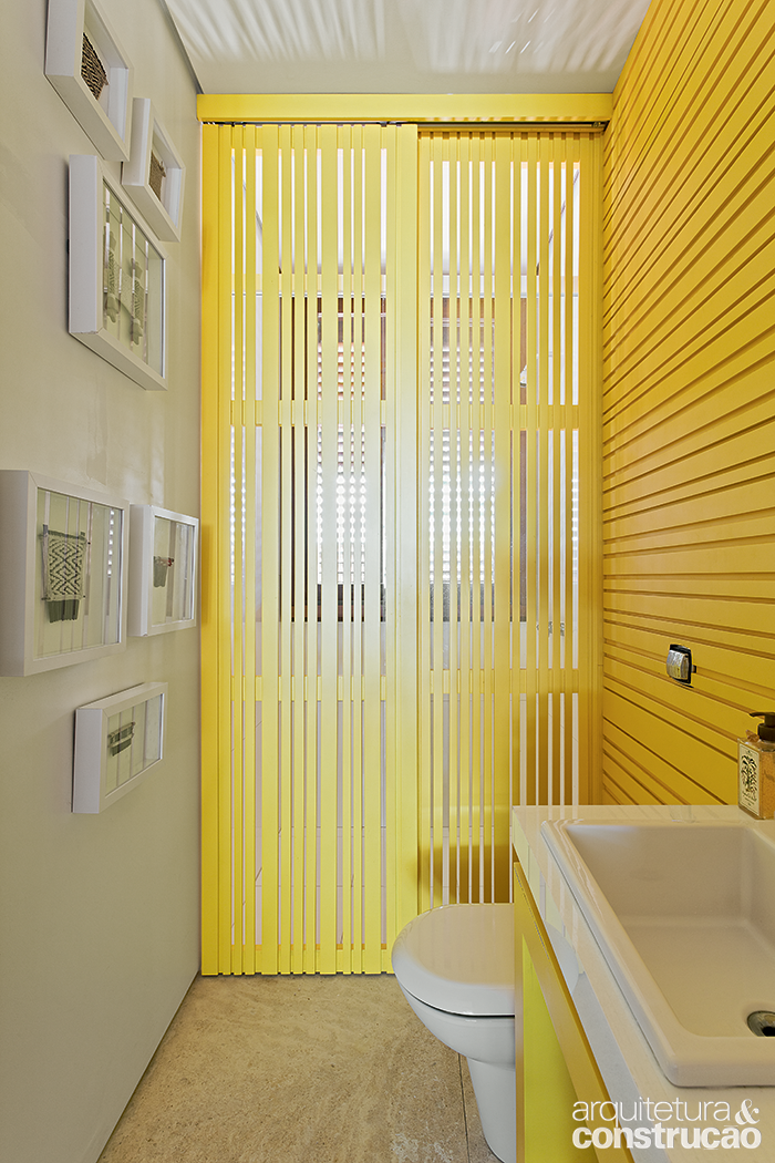 Pinceladas de amarelo colorem este ambiente com dupla fun&ccedil;&atilde;o: lavabo e banheiro. A cor est&aacute; presente no revestimento de madeira e tamb&eacute;m na divis&oacute;ria m&oacute;vel que isola a &aacute;rea do chuveiro.