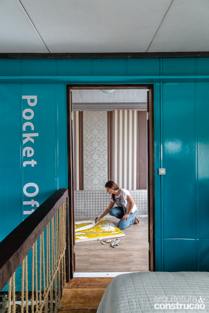 O dormitório da moradora ocupa o mezanino e dá acesso à entrada do contêiner, transformado em ateliê. Lá dentro, mais sinais de reaproveitamento – retalhos de papéis de parede vestem o ambiente. O dormitório da moradora ocupa o mezanino e dá acesso à entrada do contêiner, transformado em ateliê. Lá dentro, mais sinais de reaproveitamento – retalhos de papéis de parede vestem o ambiente.