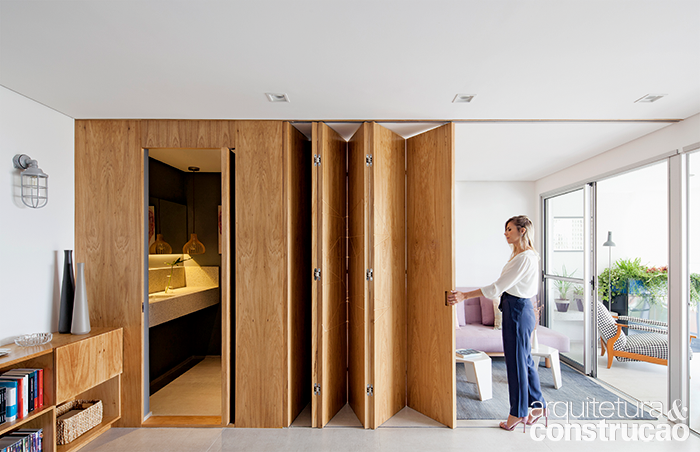 Destaque do apartamento, a porta-camar&atilde;o de freij&oacute; substituiu a parede entre quarto e sala. &ldquo;Esse tipo de fechamento possibilita a m&aacute;xima abertura do v&atilde;o, ocupando pouco espa&ccedil;o quando recolhido&rdquo;, afirma a arquiteta Aline D&rsquo;Avola, que assina a reforma. Na parte fixa (&agrave; esq.), esconde-se o lavabo.