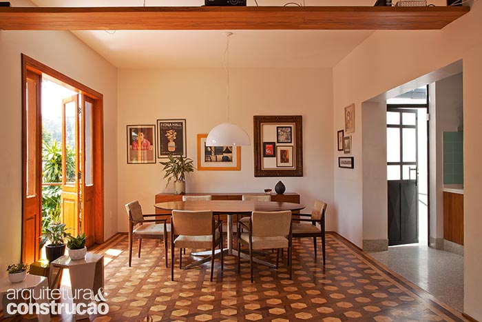 A &uacute;nica delimita&ccedil;&atilde;o entre sala de jantar, de estar e cozinha s&atilde;o os pisos originais e o granilite (novo, por&eacute;m respeitando os tons daquele que existiu ali). O acesso &agrave; garagem, no t&eacute;rreo, se d&aacute; pela escada atr&aacute;s da porta de ferro (&agrave; dir.), feita sob medida e inspirada num modelo que o casal viu em Nova York.