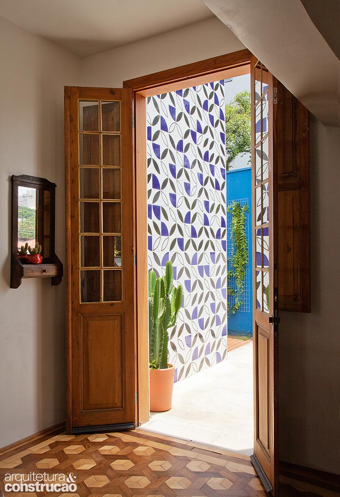 &ldquo;Tivemos que adaptar a parede para acomodar esta porta antiga, que encontramos antes de comprar a casa&rdquo;, conta a propriet&aacute;ria. Azulejos da Lurca marcam a entrada principal com acesso para o jardim.