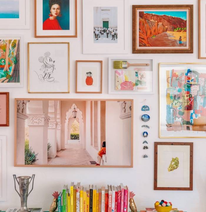 Composição colorida de quadros acima de buffet verde com livros em cima