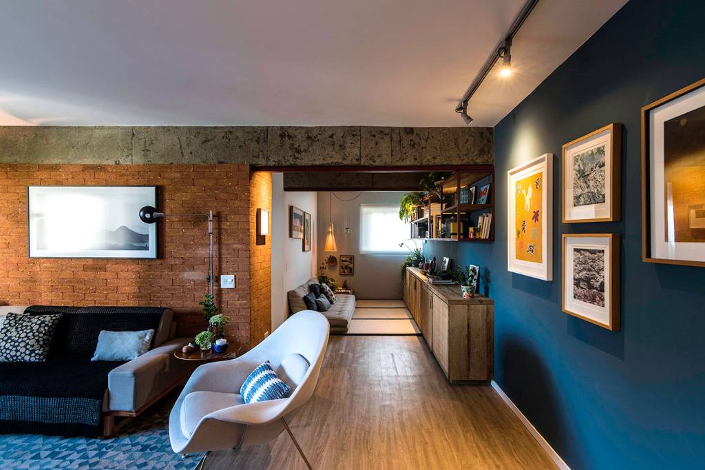 reforma-garante-personalidade-e-conforto-para-um-apartamento-de-70-m²-casa.com-hoearquitetura-eli-k-hayasaka-1-sala-de-estar Sala de estar integrada, com piso de madeira, parede azul e de tijolinhos