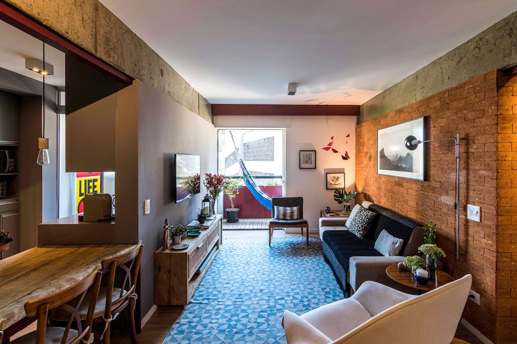 reforma-garante-personalidade-e-conforto-para-um-apartamento-de-70-m²-casa.com-hoearquitetura-eli-k-hayasaka-2-sala-de-estar Sala de estar integrada, com piso de madeira, parede de tijolinhos, ao fundo, varanda com rede