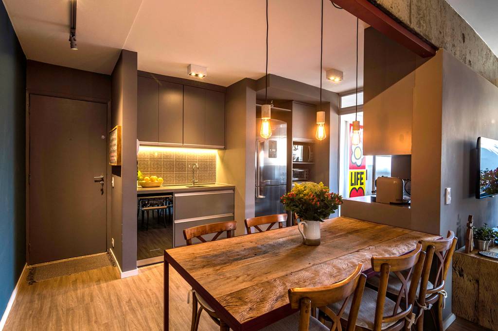 reforma-garante-personalidade-e-conforto-para-um-apartamento-de-70-m²-casa.com-hoearquitetura-eli-k-hayasaka-5-cozinha-sala-de-jantar-e-porta Sala de estar jantar, com piso de madeira, e cozinha com móveis marrons