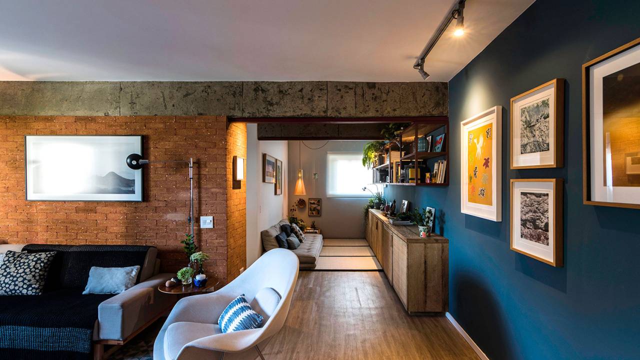 Sala de estar integrada, com piso de madeira, parede azul e de tijolinhos