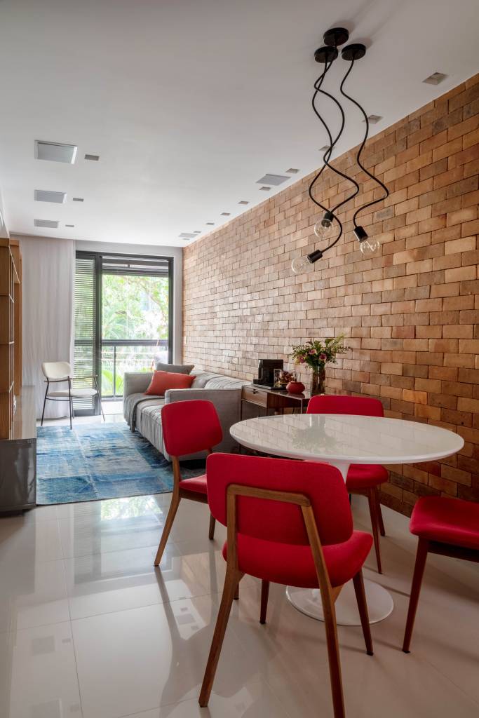14-apê-de-65-m-2-recebe-estilo-contemporâneo-urbano-e-tons-neutros Sala de estar com parede de tijolinhos e cadeiras vermelhas