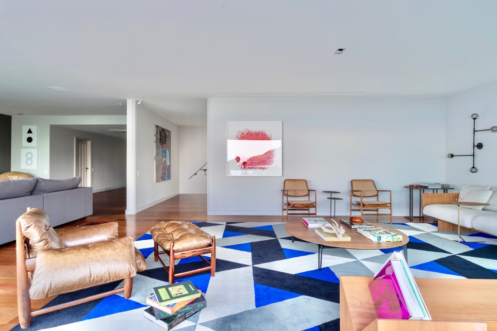 Poltronas marrons e tapete colorido em tons de azul em sala de estar