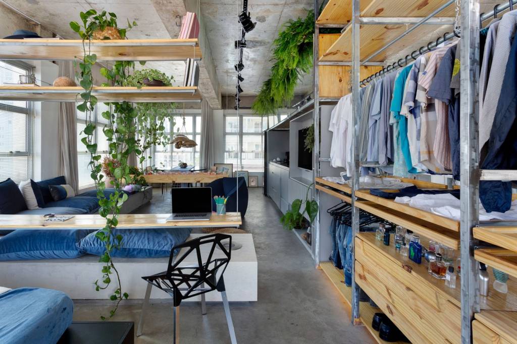arquiteto-transforma-sala-comercial-em-loft-closet-aberto-estante-suspensa-com-plantas-sofa-azul Closet aberto, estante suspensa com plantas, em ambiente comprido integrado com sala de estar e jantar.
