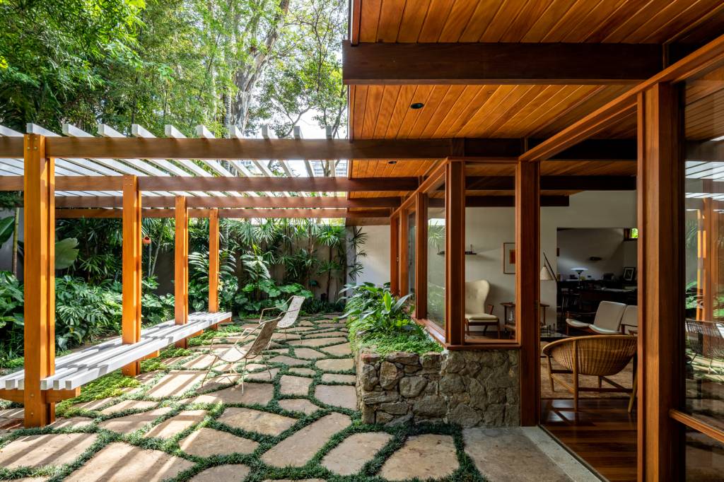 conheca-restauracao-casa-thompsons-hess-fran-parente-sala-de-estar-conectada-ao-jardim imagem mostra pátio com jardim integrado à sala de estar/tv, com pergolado e plantas ao fundo.