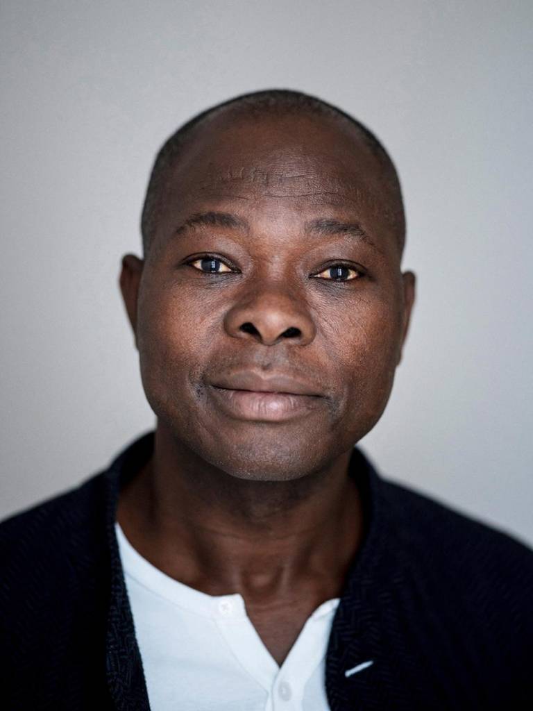 francis-kere-vencedor-pritzker-2022-lars-borges-retrato-arquiteto-kere Imagem mostra retrato do arquiteto Francis Kéré. Ele é um homem negro vestindo camisa branca sob paletó preto.