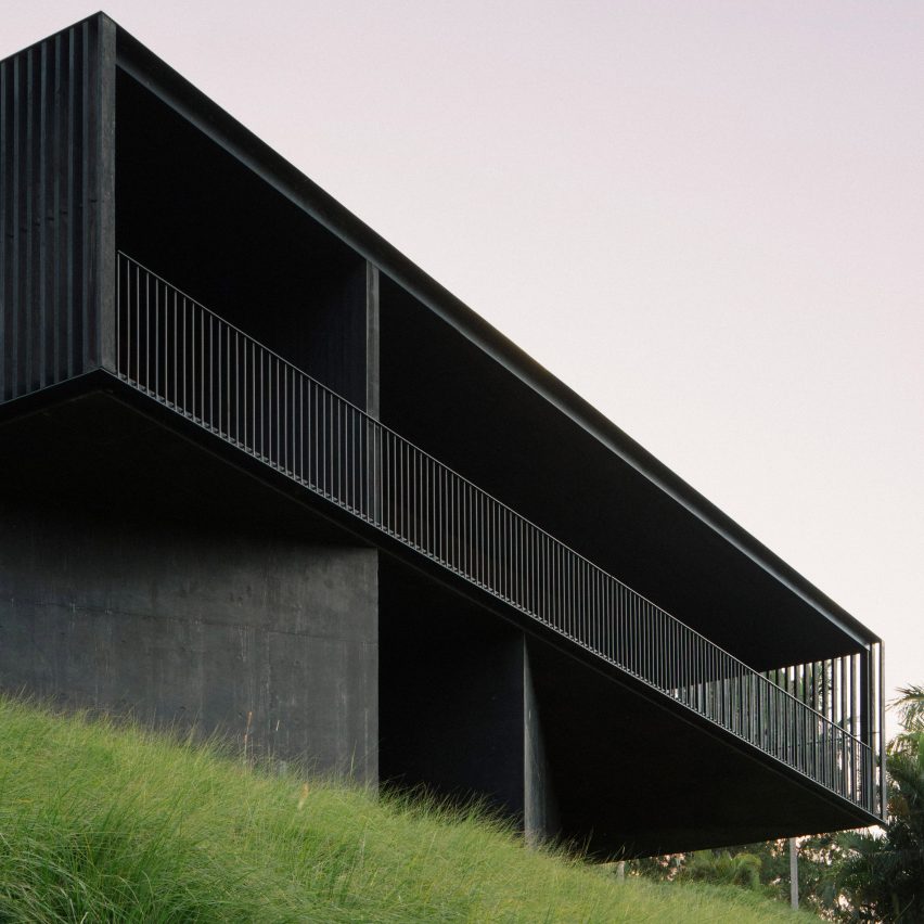 quem-disse-concreto-precisa-ser-cinza-ben-hosking-casa-fachada-concreto-preto Casa com fachada toda preta com ripado de madeira, grama verde e céu cinza.