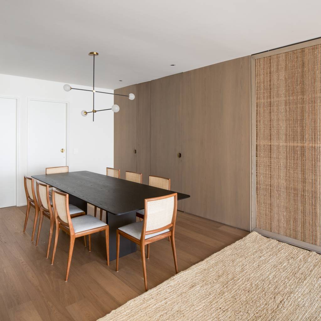 19-base-neutra-cores-escuras-e-design-assinado-formam-este-apê-de-170-m-2 Sala de jantar com mesa e cadeiras de design e painel de madeira