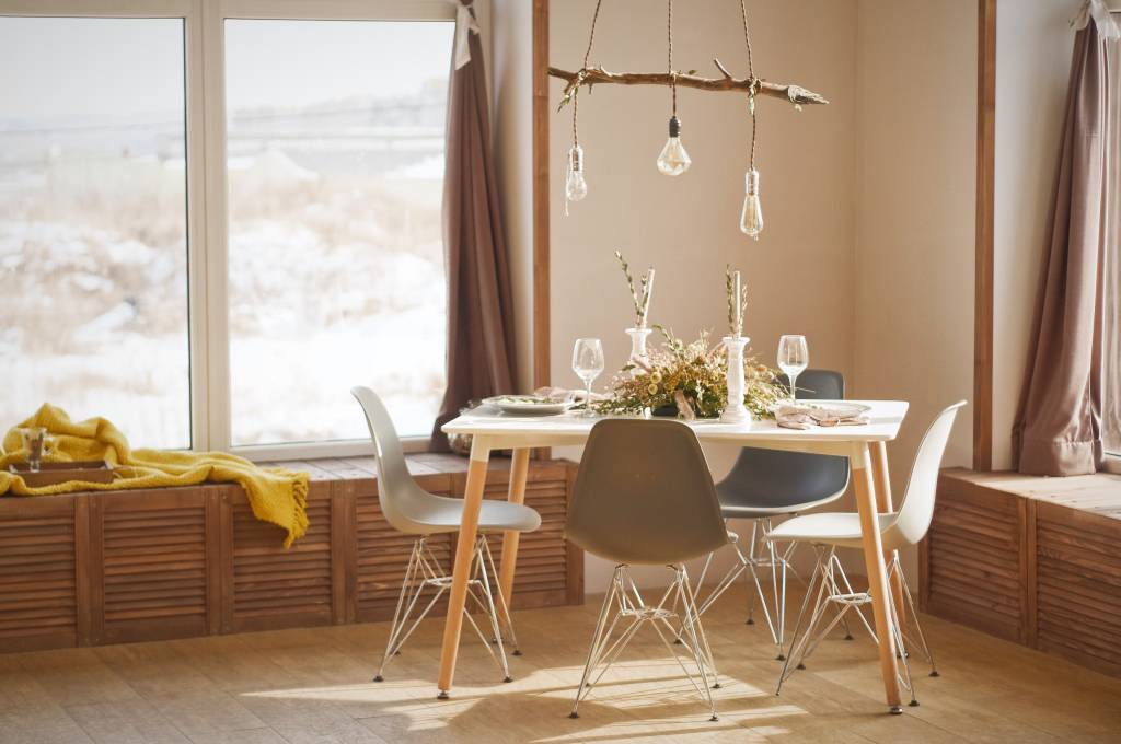 4-dicas-para-escolher-a-mesa-de-jantar-ideal-para-sua-casa-daniil-silantev-Unsplash-móveis-decoração-design Mesa de jantar de quatro lugares, sob luminária de estrutura de madeira rústica em frente a uma janela.