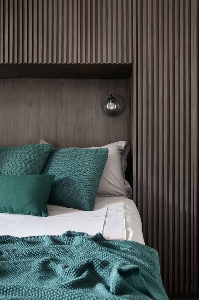 Apartamento masculino no bairro Santa Rosa em Niterói assinado pelo STUDIO LIVIA AMENDOLA _ foto 13-quarto-cama-almofada-madeira-ripada Quarto com cama de casal; revestimento de madeira ripada na cabeceira