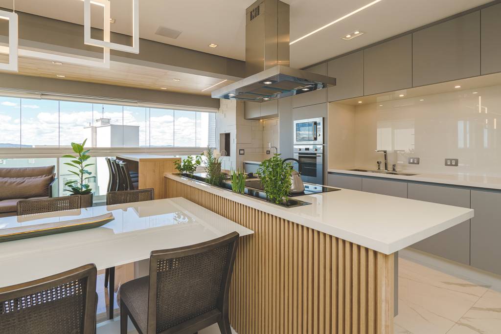 Moderno-e-orgânico-a-trend-para-se-reconectar-com-a-natureza-Casa.com.br-Marcelo-Stammer-decoração-dicas-inspiração Cozinha em tons complementares de branco, bege e marrom. A bancada da pia forma uma ilha no ambiente. Atrás da pia está a calha molhada, em que se encontram ervas e temperos plantados.