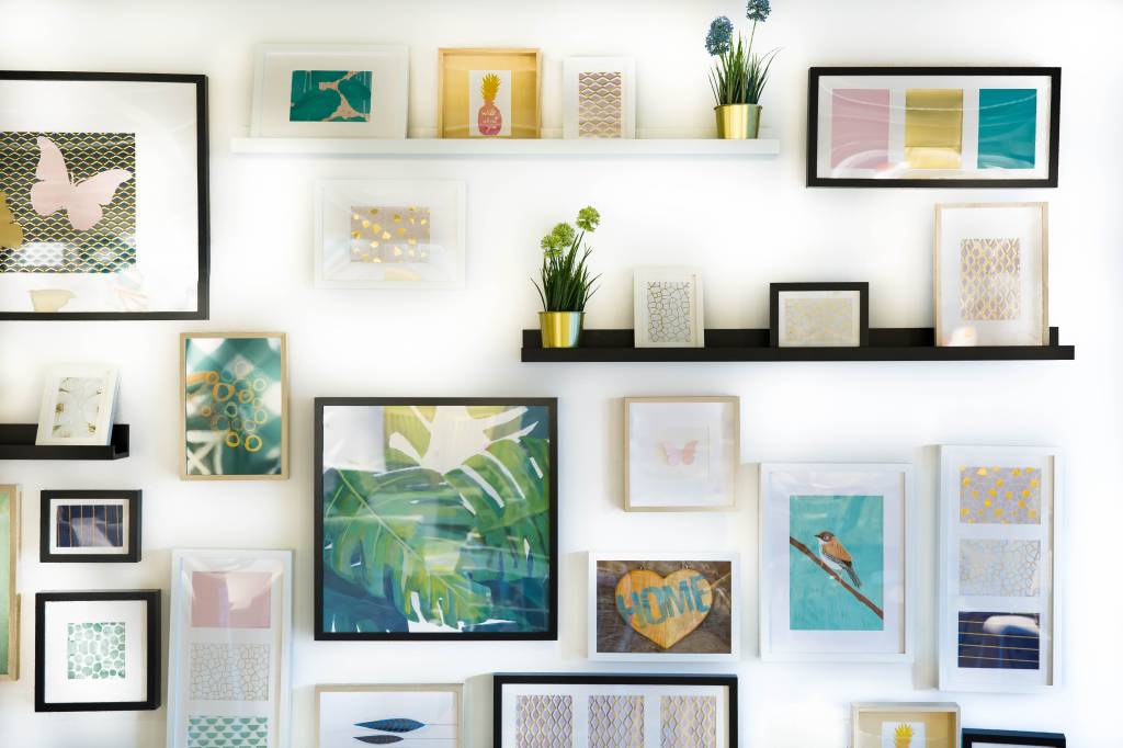 como-escolher-moldura-quadro-jonny-caspari-KuudDjBHIlA-unsplash Parede branca com prateleiras; quadros penduradod