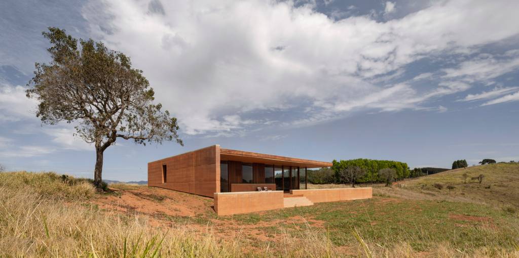 taipa-de-pilao-revisitada-em-casa-em-cunha-federico-cairoli-fachada-taipa-casa-de-campo Fachada de casa em taipa de pilão, com linhas retas, em ambiente rural e isolada na paisagem.