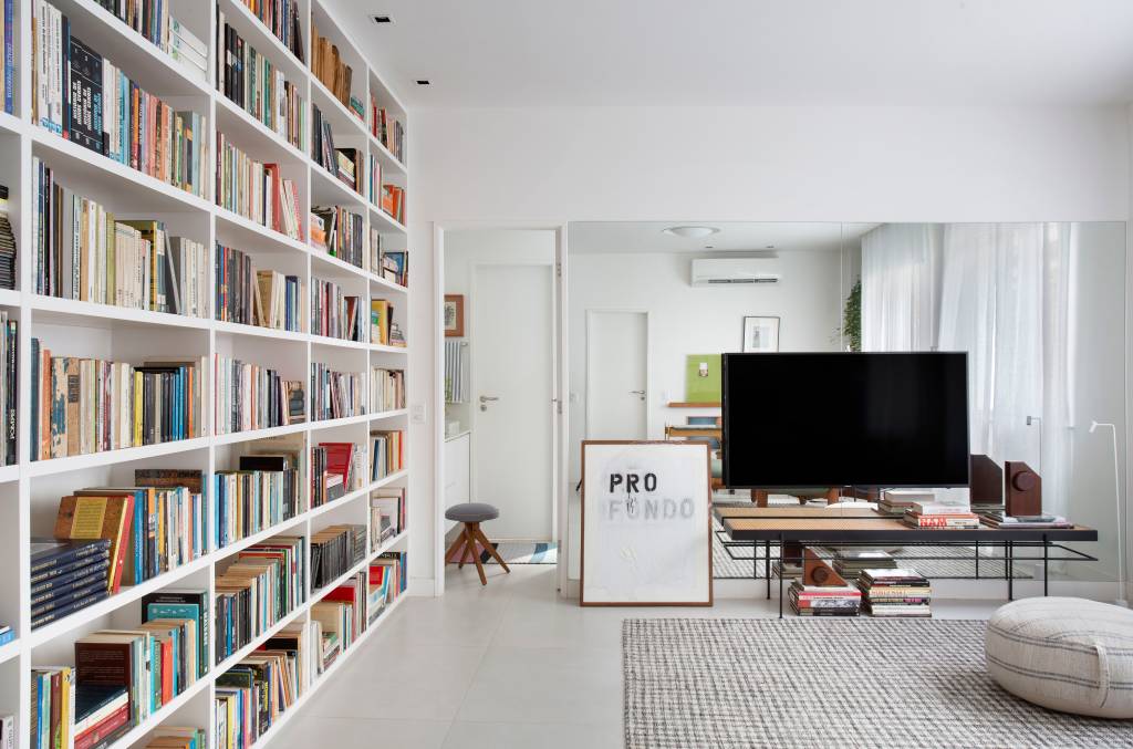 Sala de estar com base branca e estante com muitos livros