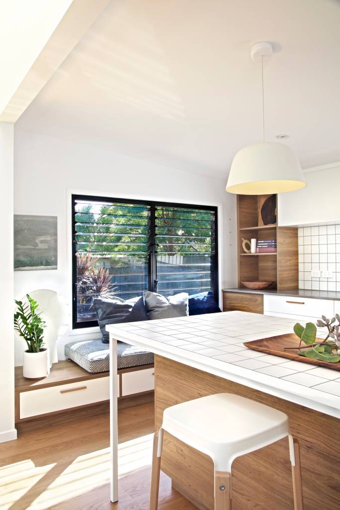 10-casa-de-180-2-transforma-rodape-em-estante-de-livros Cozinha com janela para exterior e natureza, bancada de pedra branca e luminária minimalista