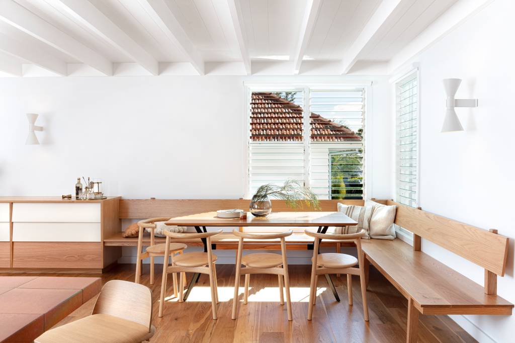 10-casa-recebe-extensao-contemporanea-com-detalhes-em-terracota Sala de jantar com bancos de madeira frente à parede branca