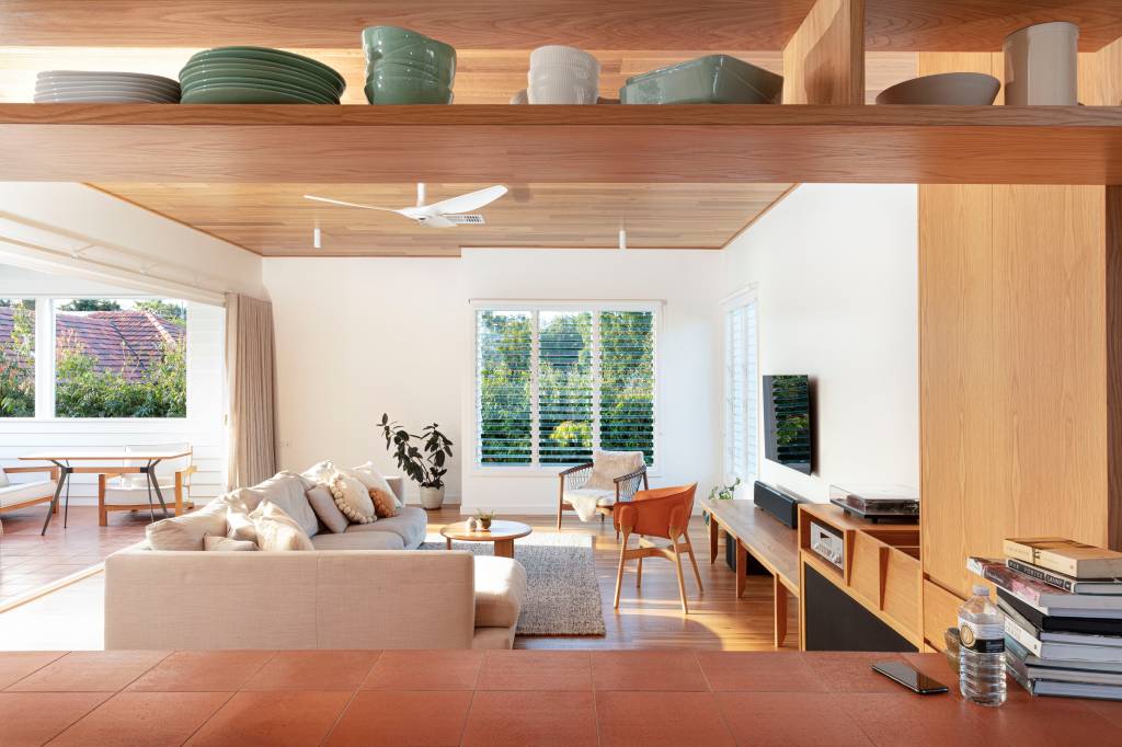 14-casa-recebe-extensao-contemporanea-com-detalhes-em-terracota Sala de estar com janela para paisagem natural, sofá branco e móveis de madeira