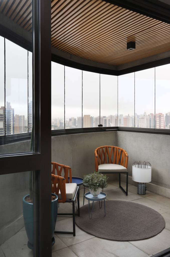 14-estilo-industrial-arte-e-integracao-marcam-este-apartamento-em-sao-paulo Varanda com duas poltronas e vista para São Paulo