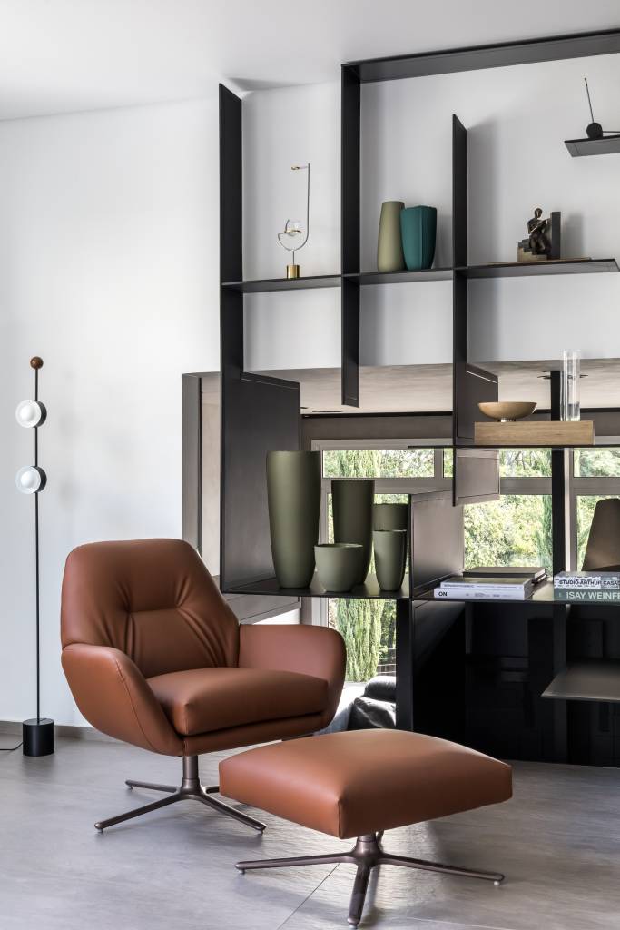 2-contemporaneo-e-industrial-formam-esta-casa-de-220-m-2-em-curitiba Sala de estar com poltrona marrom, luminária de piso e estante modular ao fundo