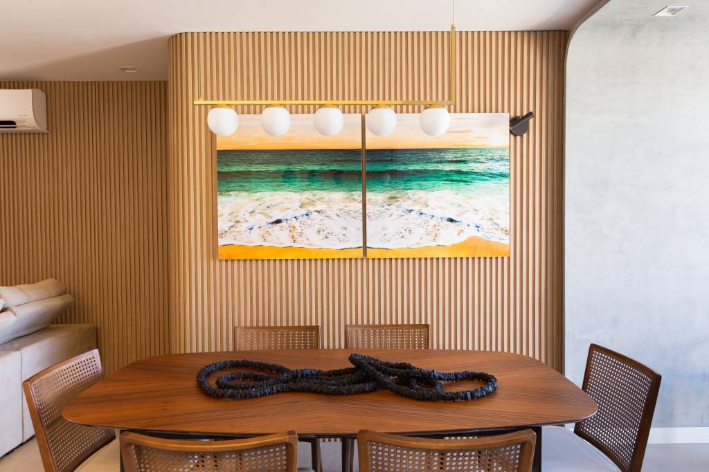 2-formas-organicas-e-esolhas-suaves-pontuam-ape-de-80-m-2-em-brasilia Sala de jantar com mesa e cadeiras de madeira e painel arredondado