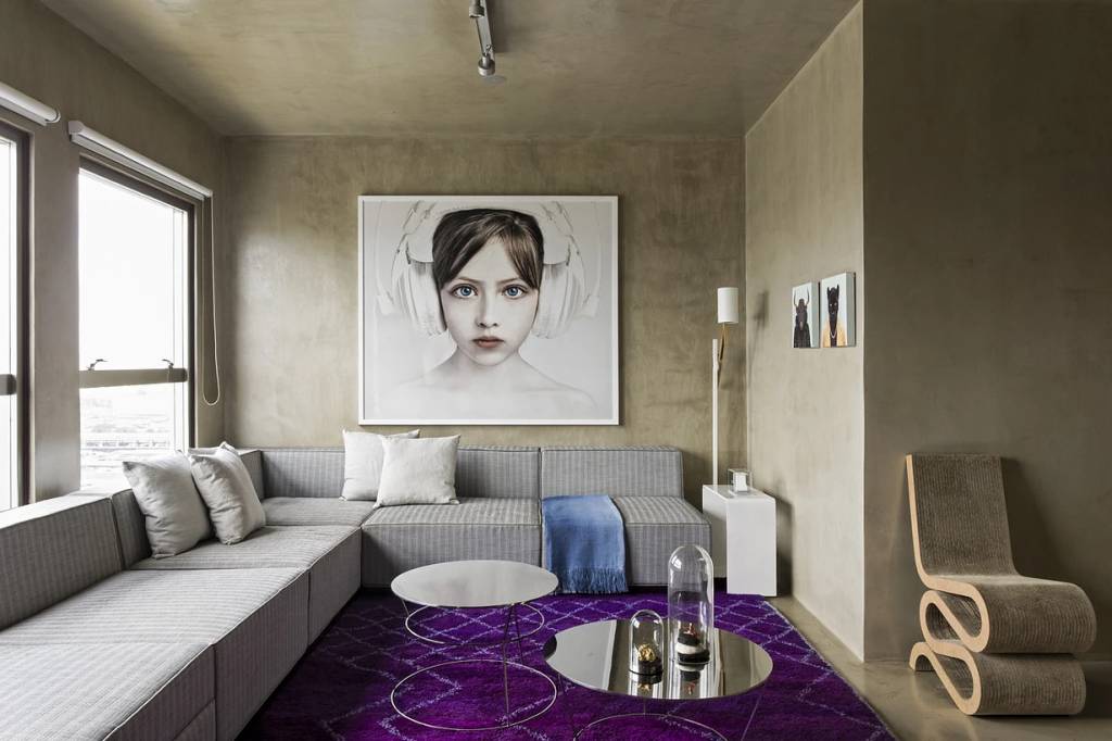 5-dicas-ampliar-apartamentos-pequenos-landhi-Diego Revollo Arquitetura-08 Sala de estar com sofás cinzas e tapete roxo; parede em cimento queimado