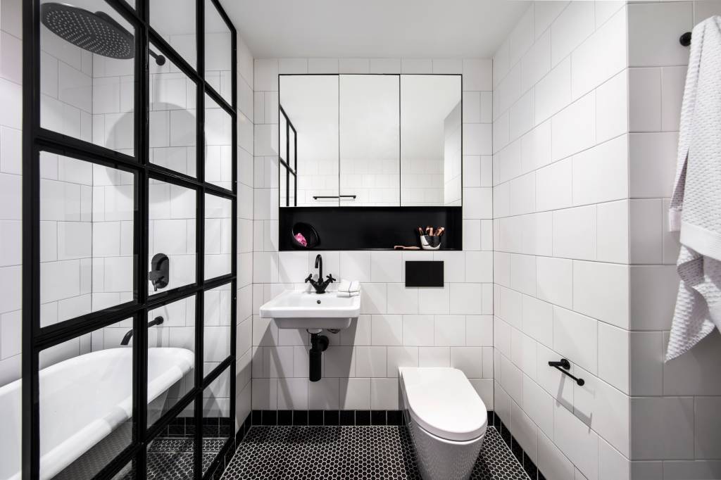 7-armazem-de-145-m-2-ganha-estilo-industrial-e-vira-casa-e-estudio-de-artista Banheiro com azulejos brancos e detalhes pretos, box de vidro